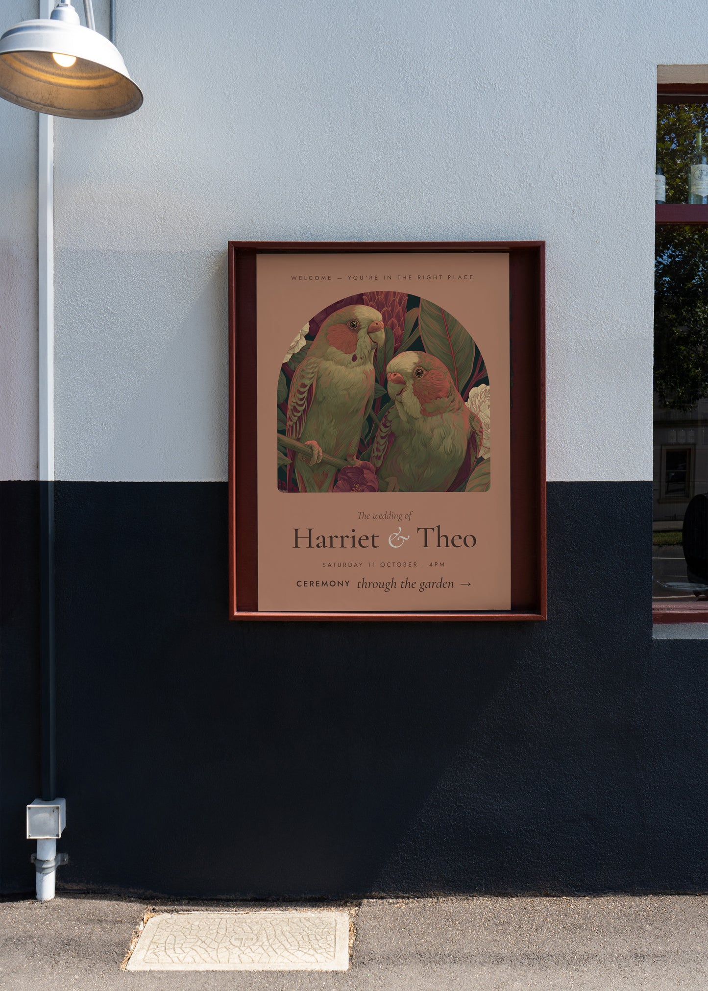 Framed artwork of parrots on a wall with a lamp and plant in the background
